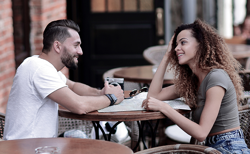 Young couple sitting outside talking to eachother.